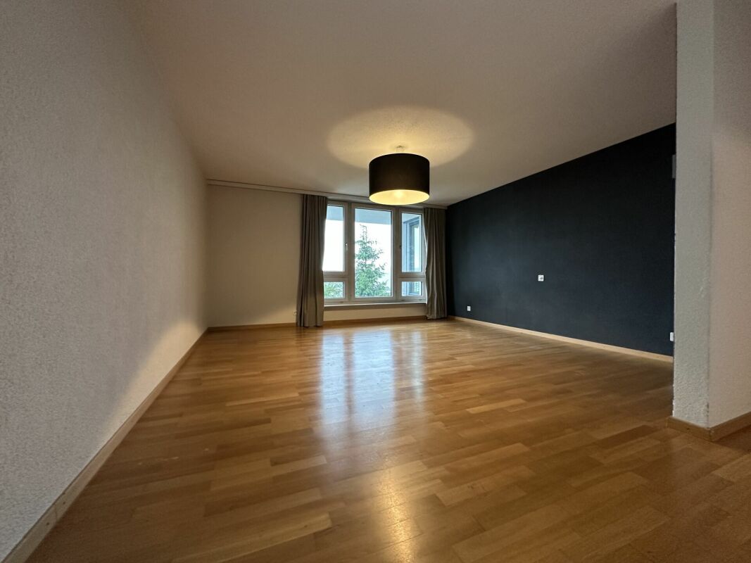 Leerer Wohnraum mit Parkett und dunkler Akzentwand