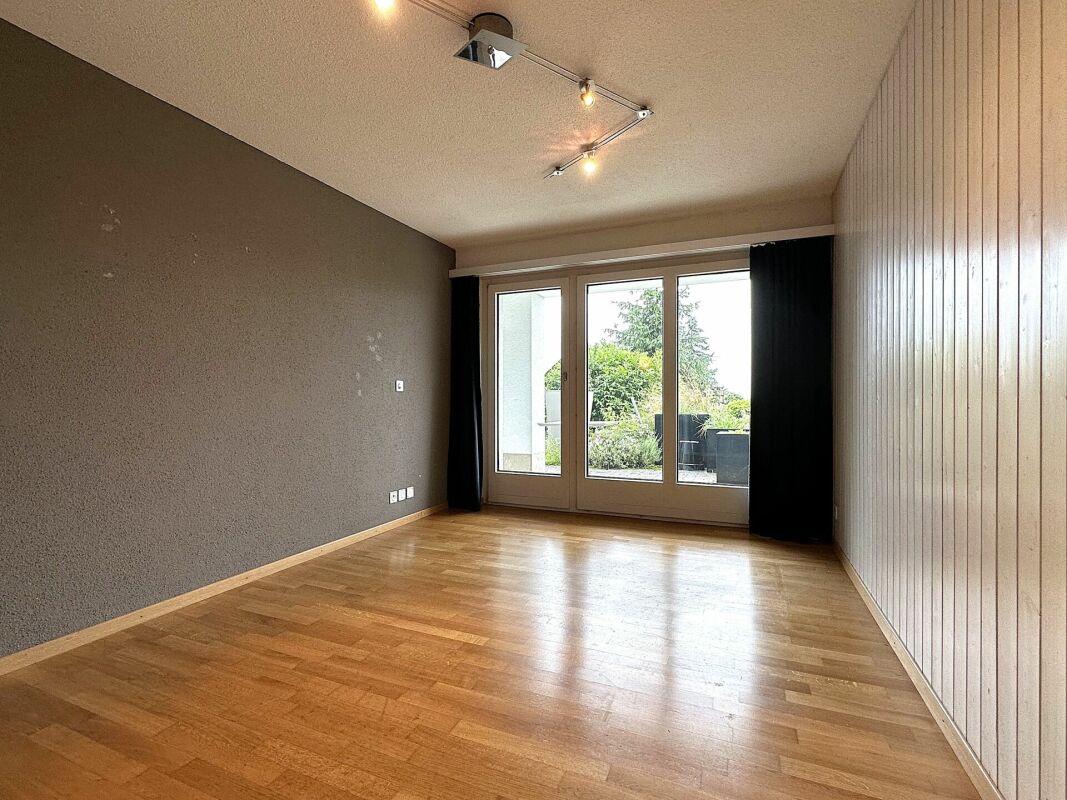 Leerer Wohnraum mit Holzfußboden und Gartentür