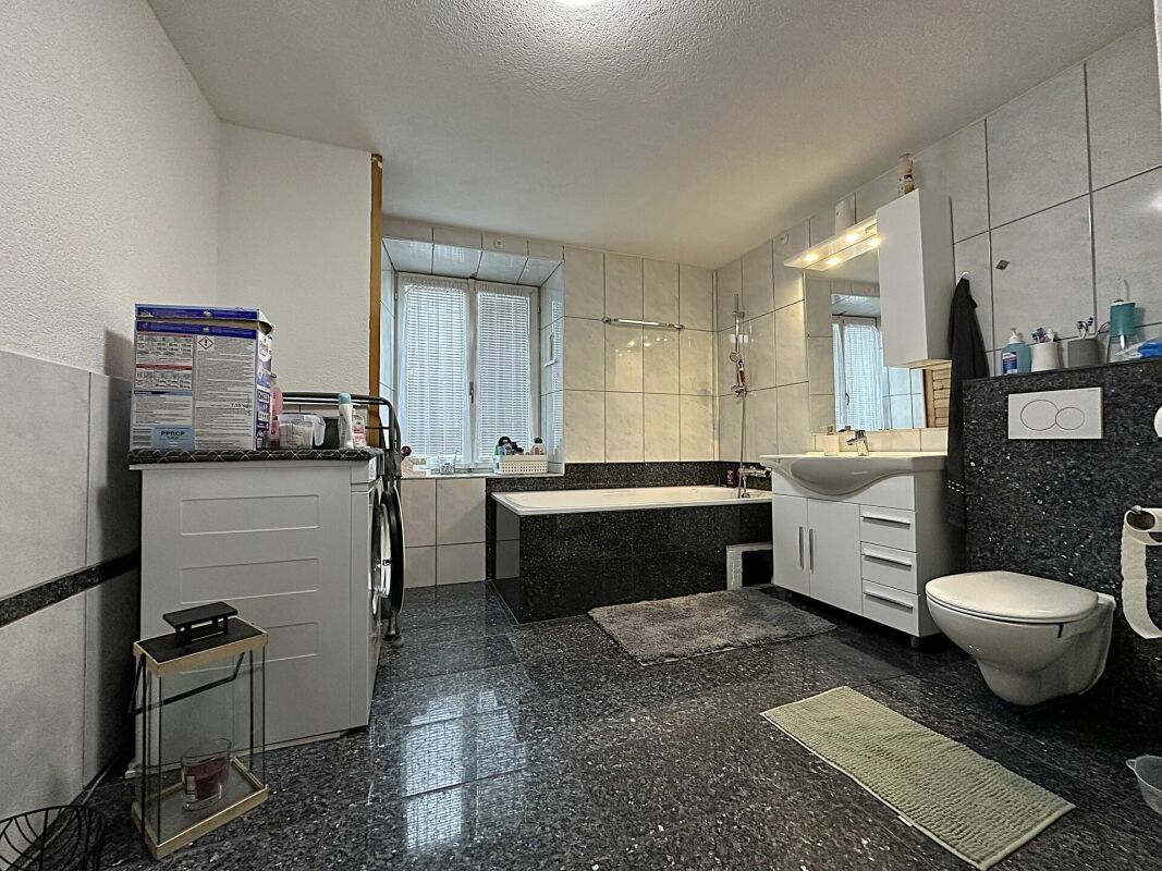 Modernes Badezimmer mit dunklem Steinboden und großem Spiegel
