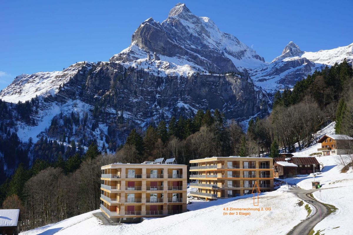 Bergresort mit Apartmenthäusern vor verschneiten Gipfeln