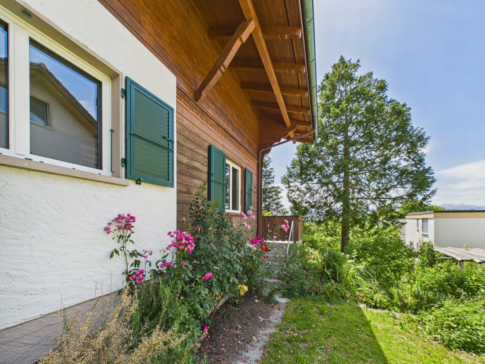 Hausfassade mit Holzverkleidung und Gartenblick