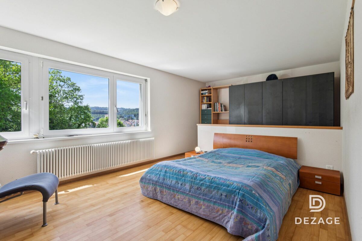 Helles Schlafzimmer mit großem Fenster und Blick ins Grüne