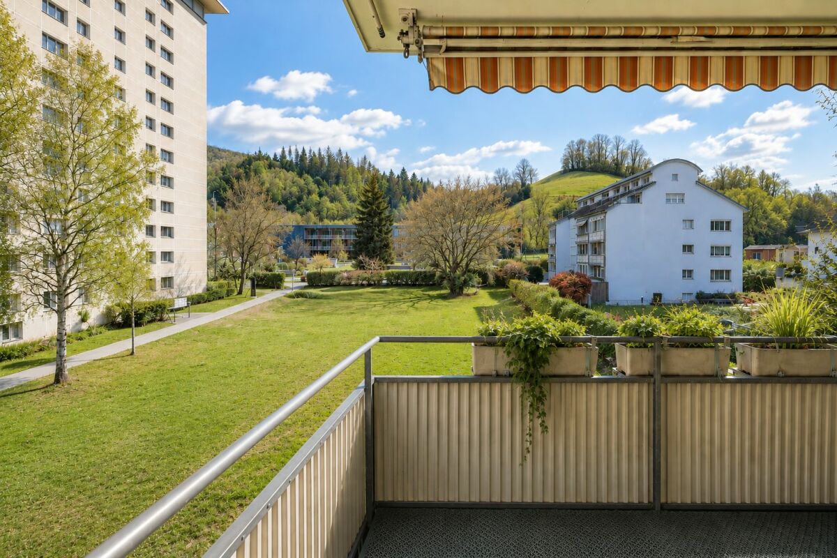 Blick vom Balkon in eine grüne Wohnanlage