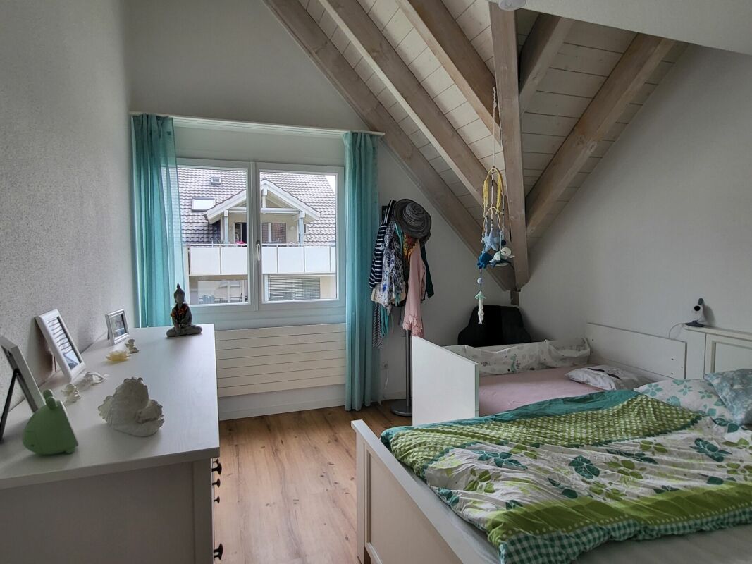 Dachgeschoss-Schlafzimmer mit sichtbaren Holzbalken