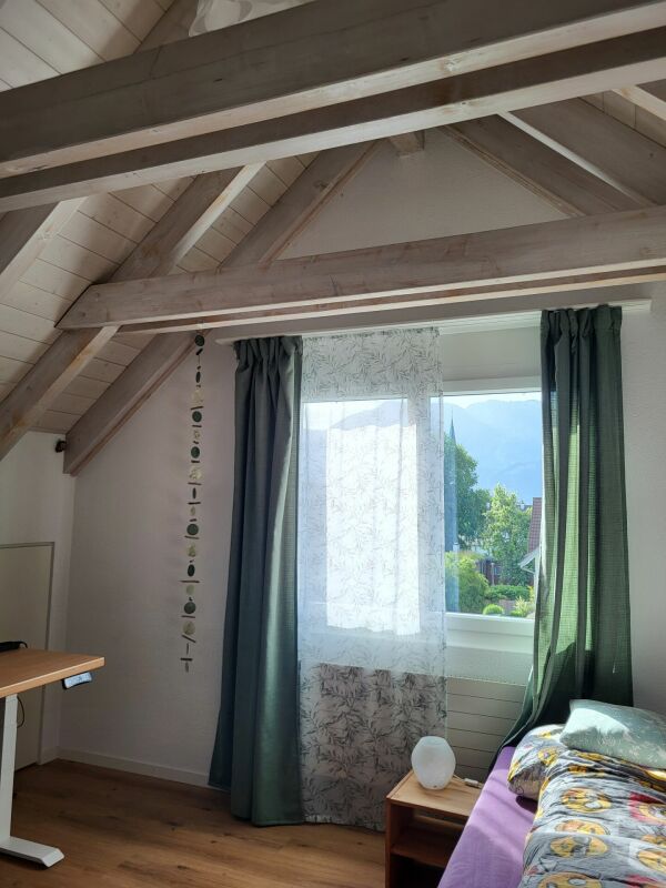 Dachgeschoss-Schlafraum mit sichtbaren Holzbalken