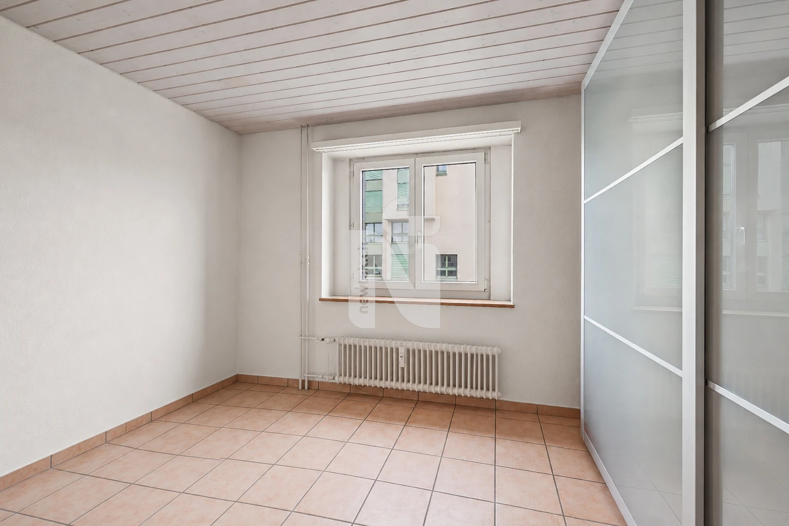 Helles, leeres Zimmer mit Fenster und Heizkörper