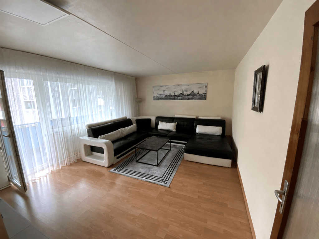Wohnzimmer mit Ecksofa und großer Fensterfront
