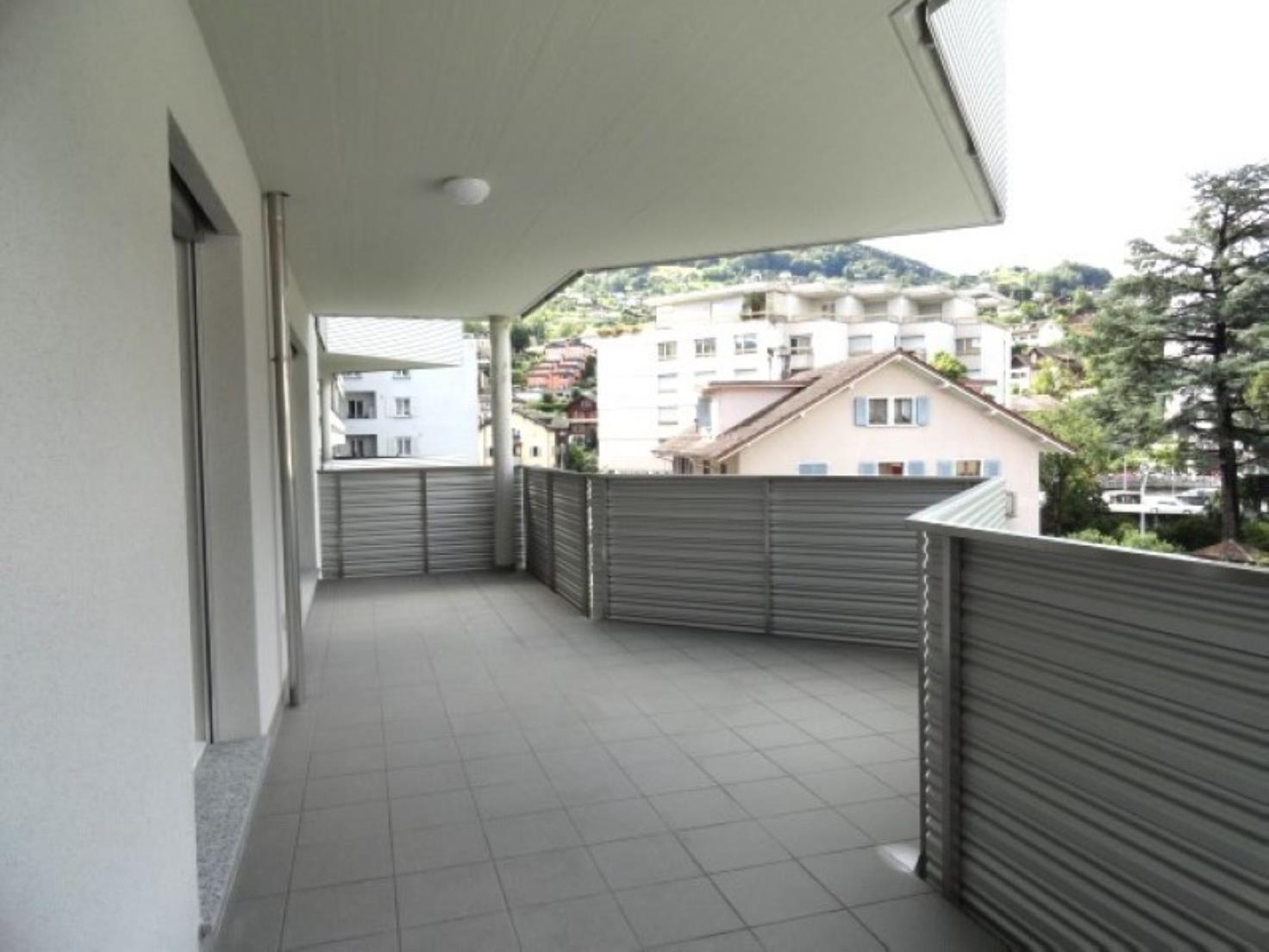Balkon mit Blick auf Wohnhäuser und Grünhügel