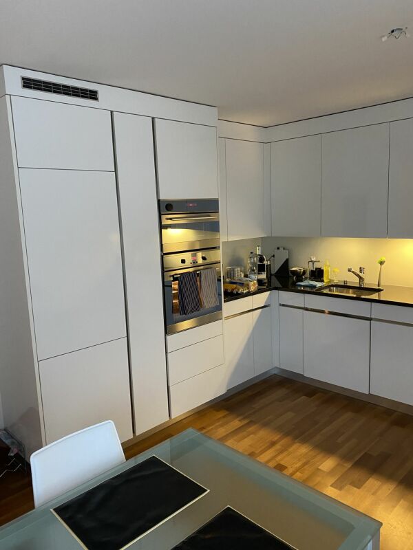 Moderne weiße Einbauküche mit Glas-Esstisch