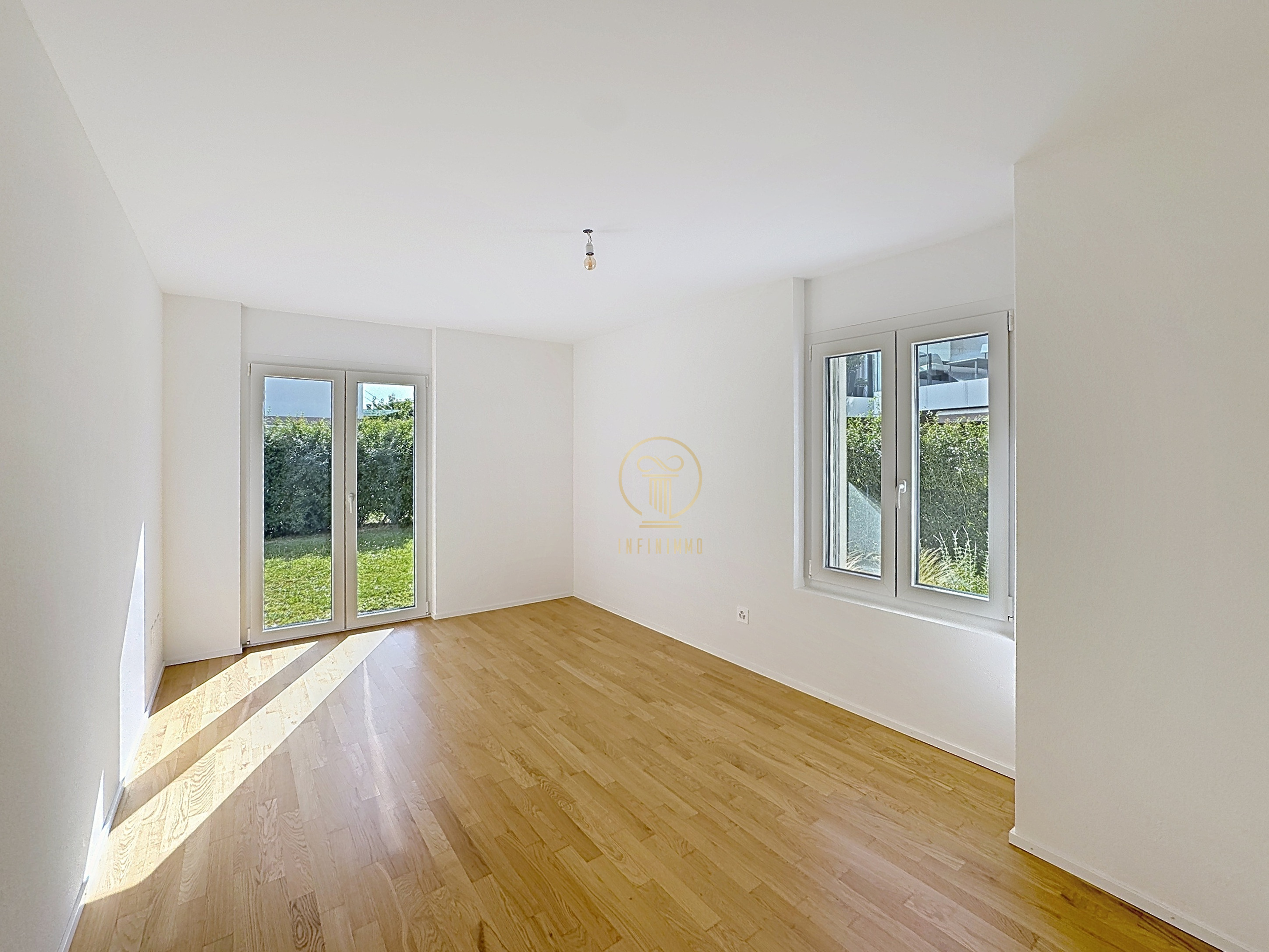 Heller leerer Raum mit Holzfußboden und großen Fenstern