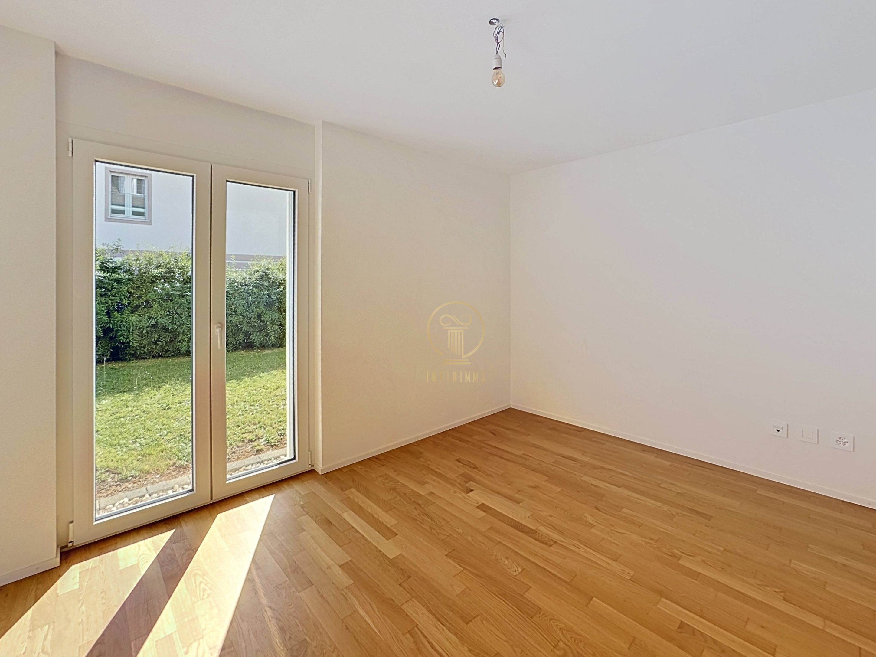 Heller leerer Raum mit Terrassentür und Holzboden