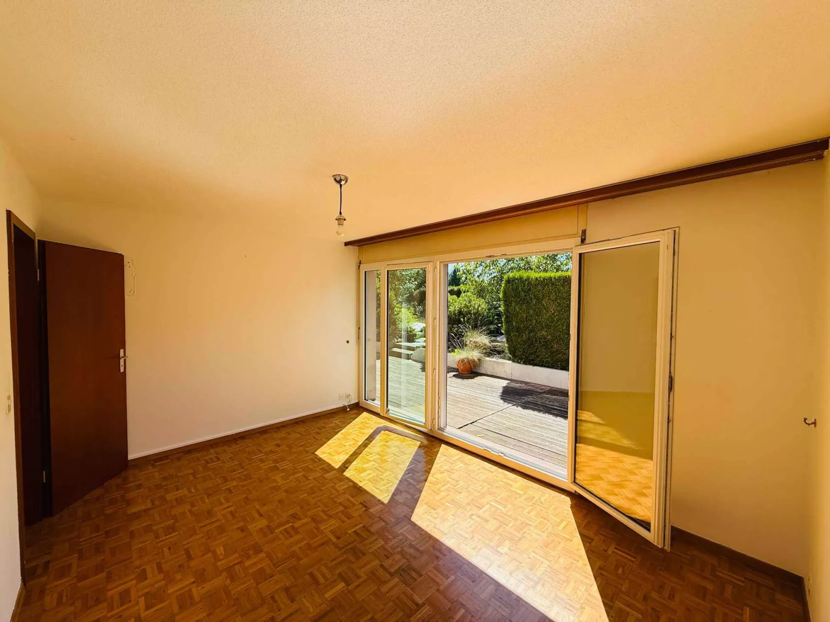 Leeres Zimmer mit Terrassentür und Gartenblick