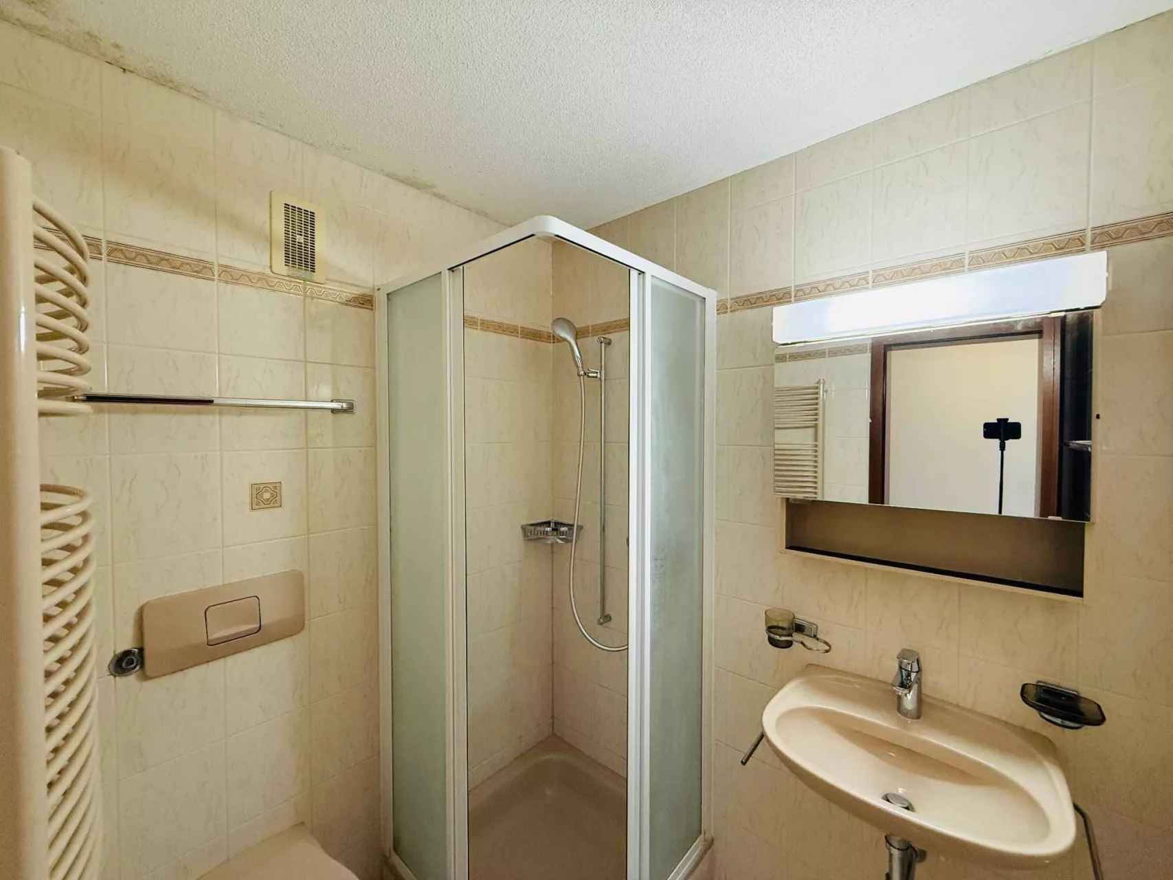 Kleines Badezimmer mit Duschkabine und Waschtisch