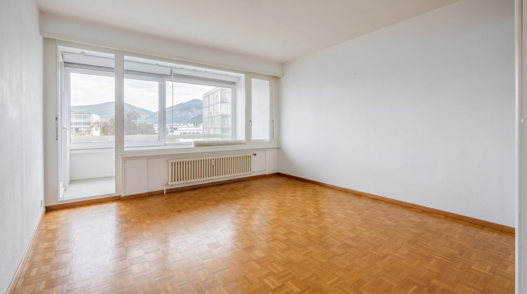 Heller leerer Wohnraum mit Balkon und Bergblick