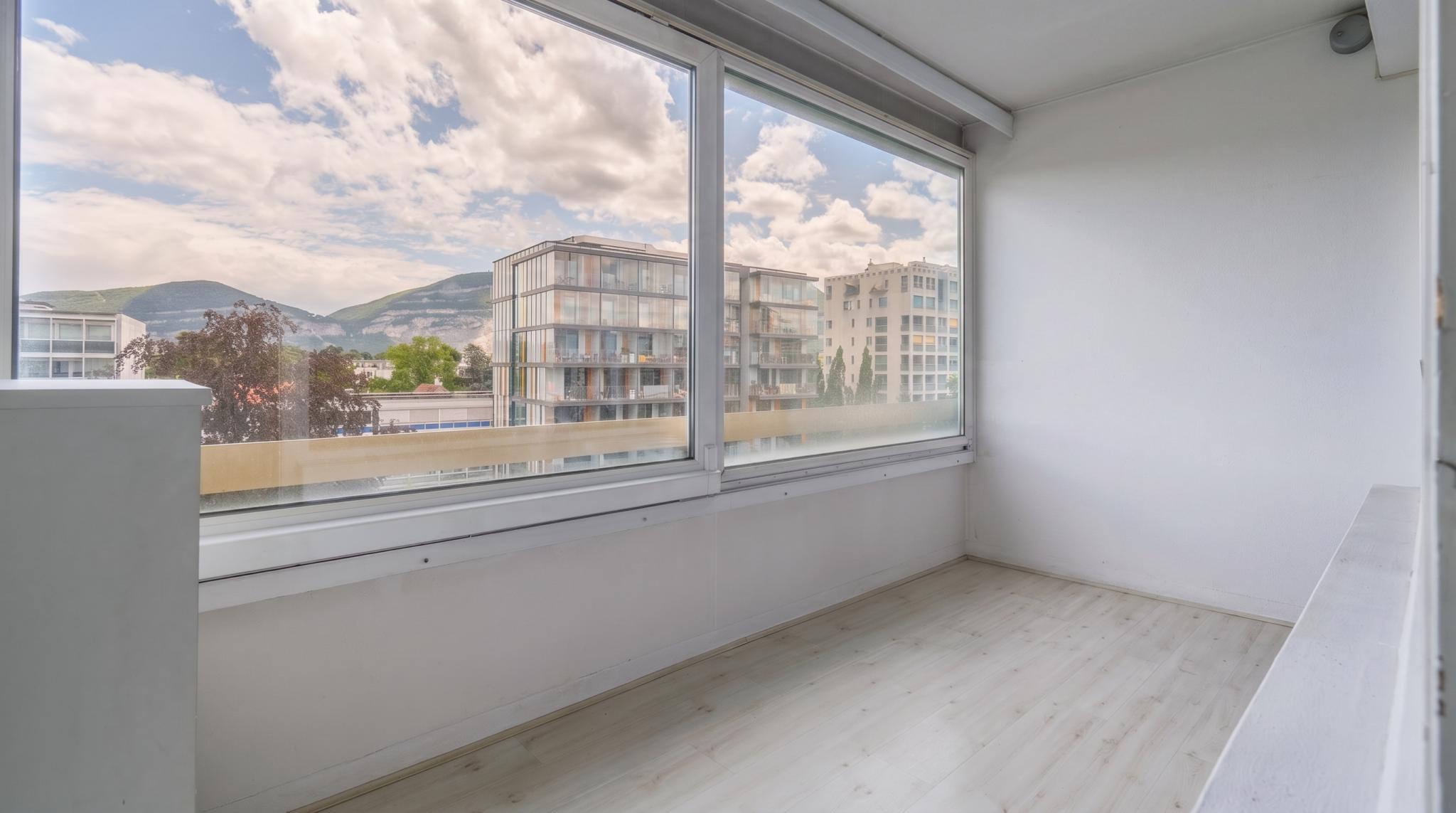 Heller Balkon- oder Wintergartenbereich mit Ausblick auf Stadt und Berge