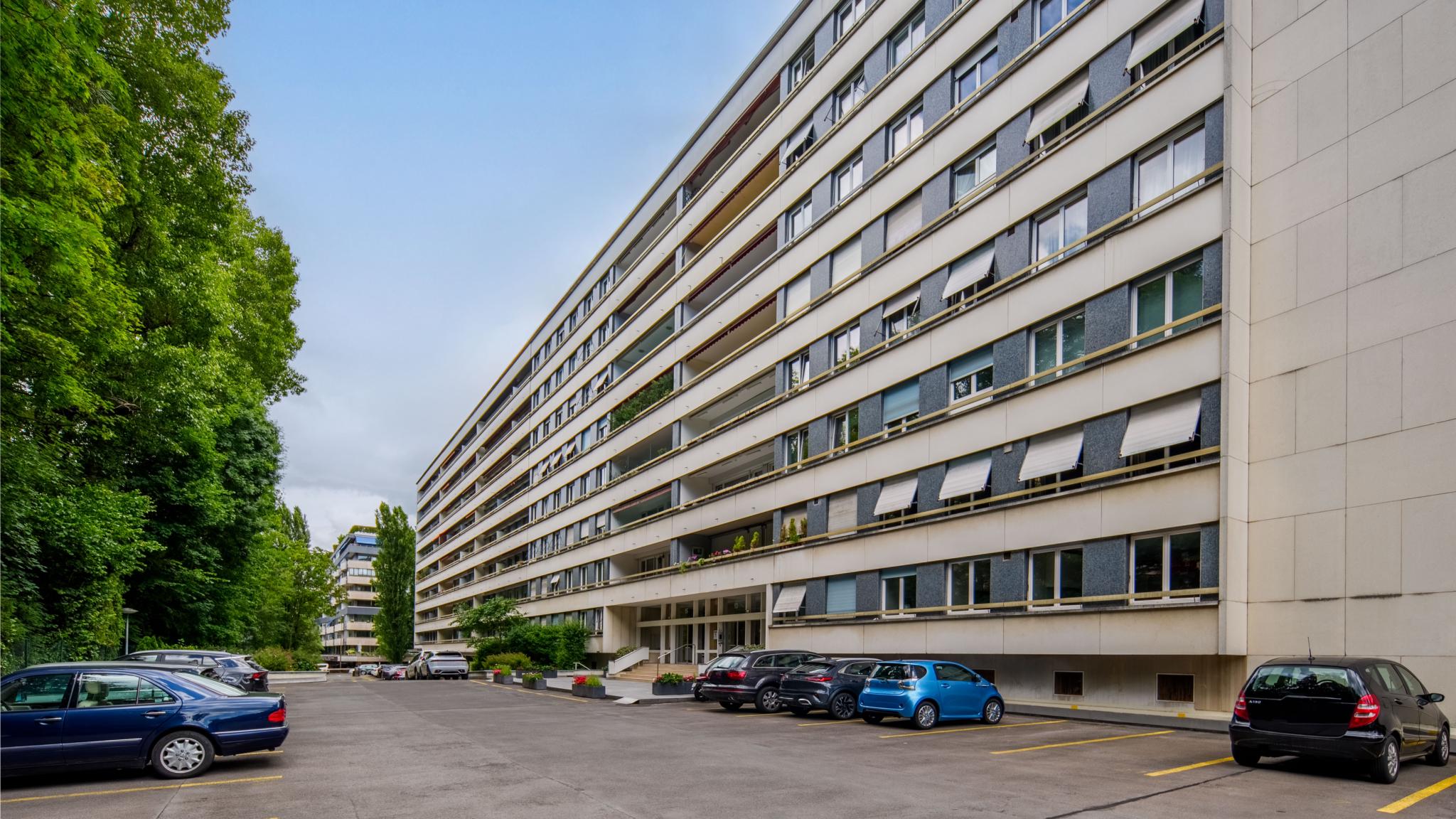 Außenansicht eines langen Mehrfamilienhauses mit Parkplatz