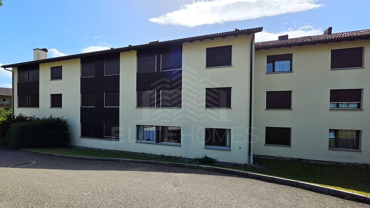 Mehrfamilienhaus mit Putzfassade und dunklen Fensterläden