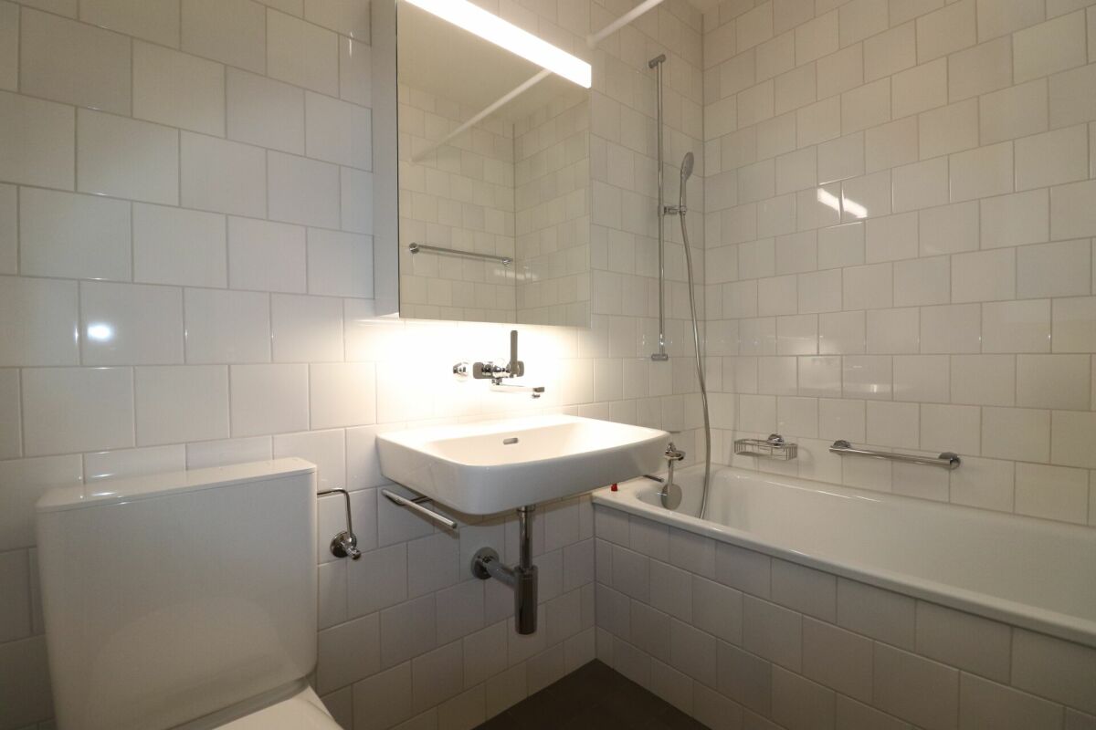 Hell gefliestes Badezimmer mit Wanne und Waschbecken