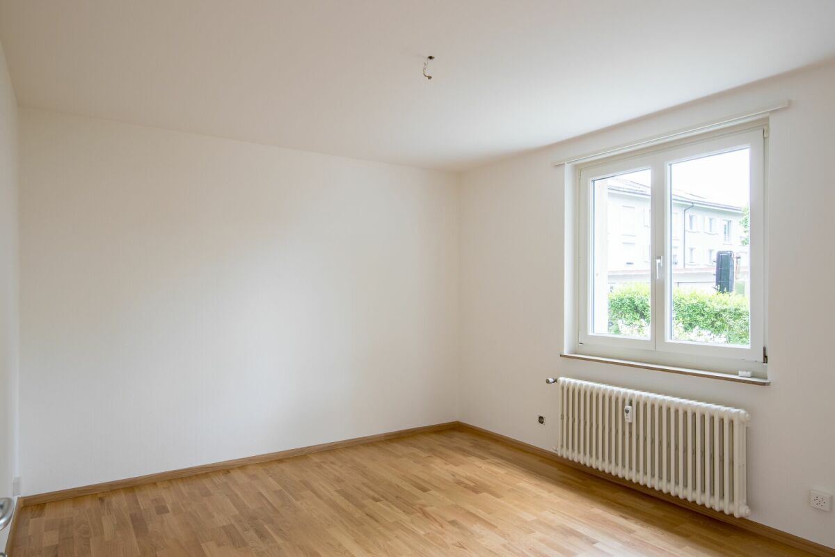 Leerer, heller Wohnraum mit Fenster und Heizkörper