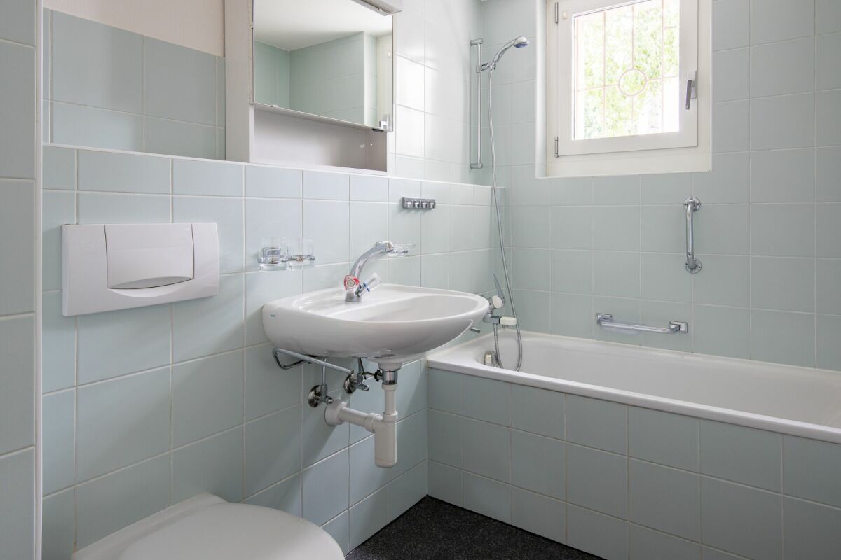 Hell gefliestes Badezimmer mit Badewanne und Waschbecken