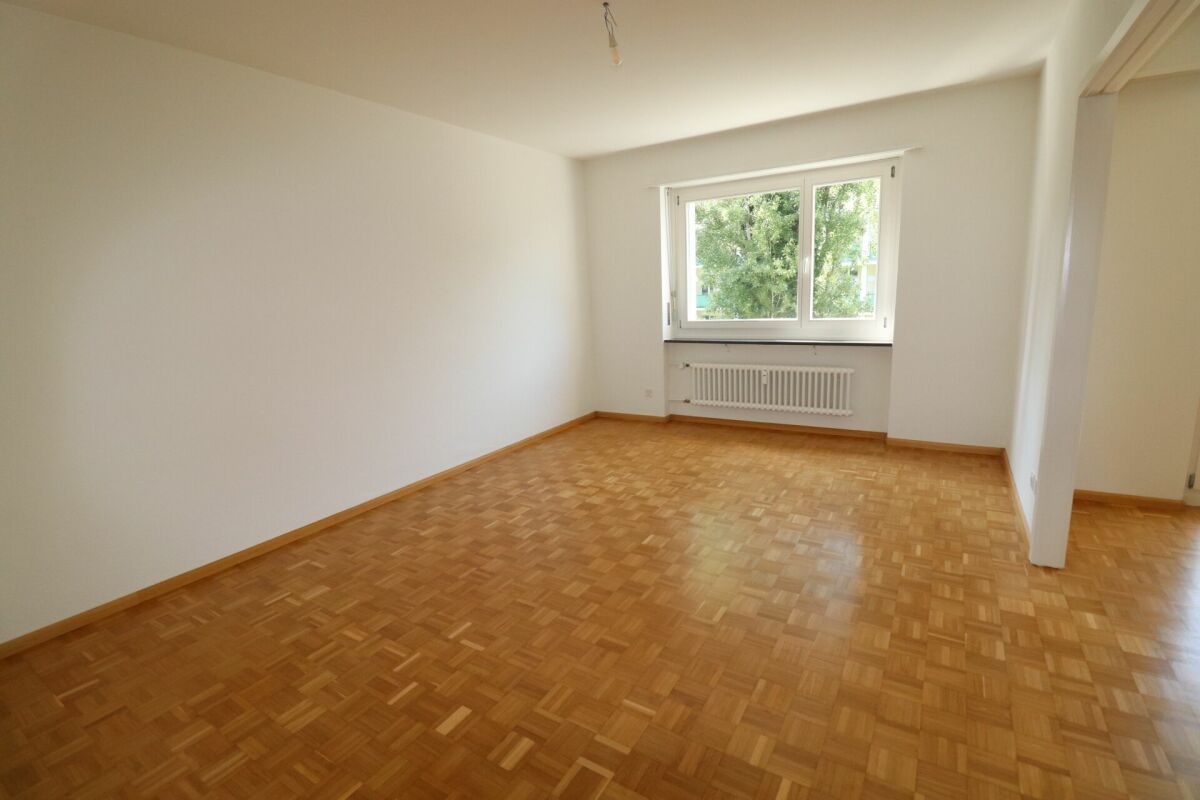 Leerer Wohnraum mit Parkett und Fenster