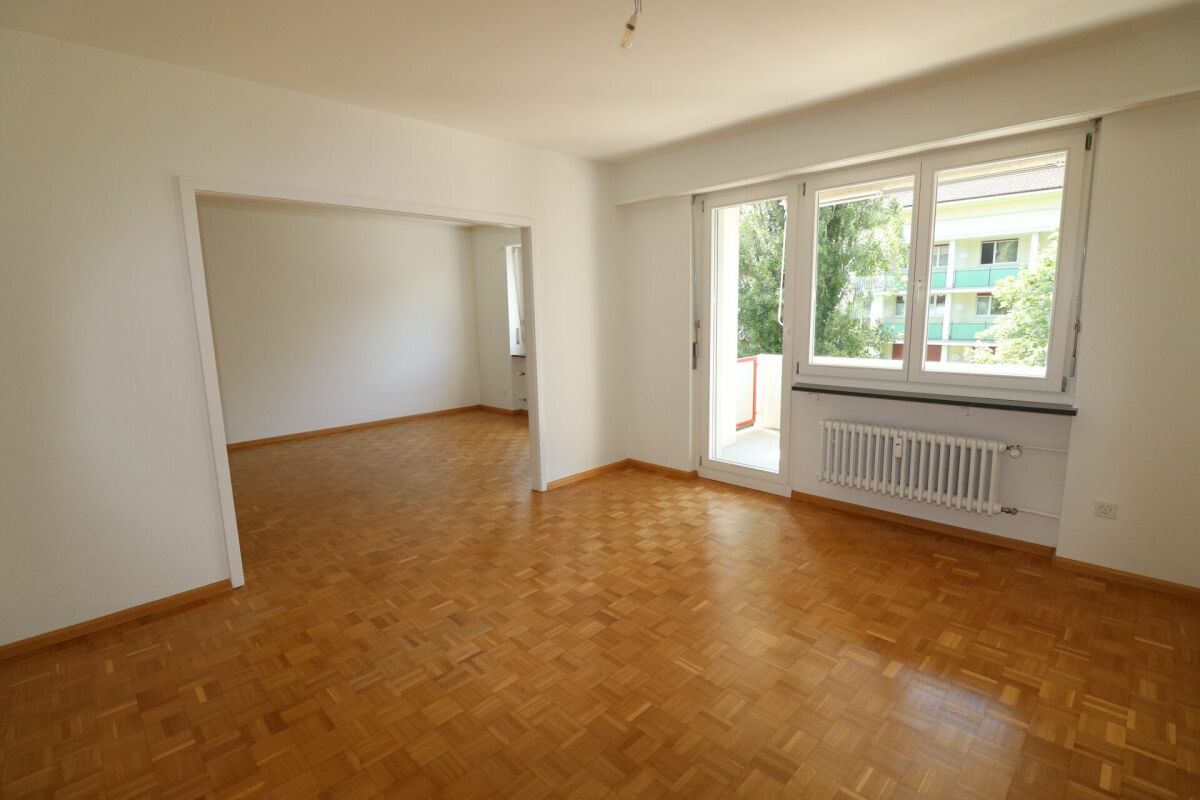 Heller leerer Wohnraum mit Balkon und Blick ins Grüne