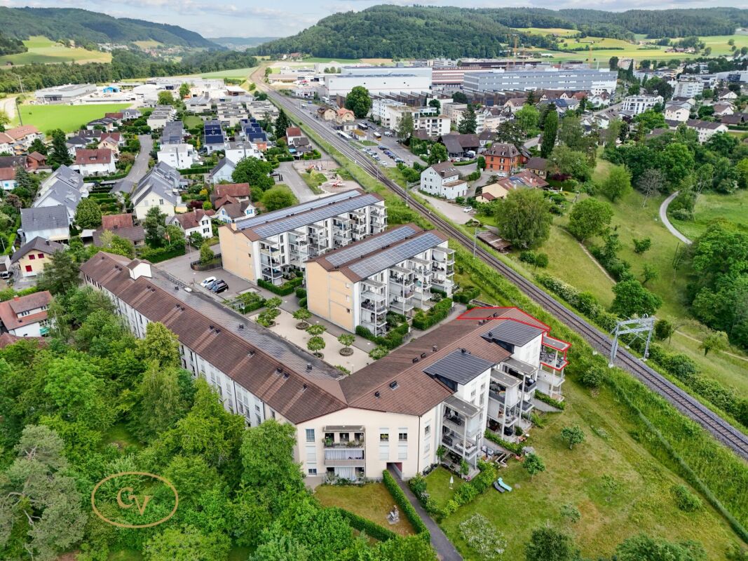 Luftaufnahme eines Wohn- und Gewerbegebiets mit Mehrfamilienhäusern und Bahntrasse