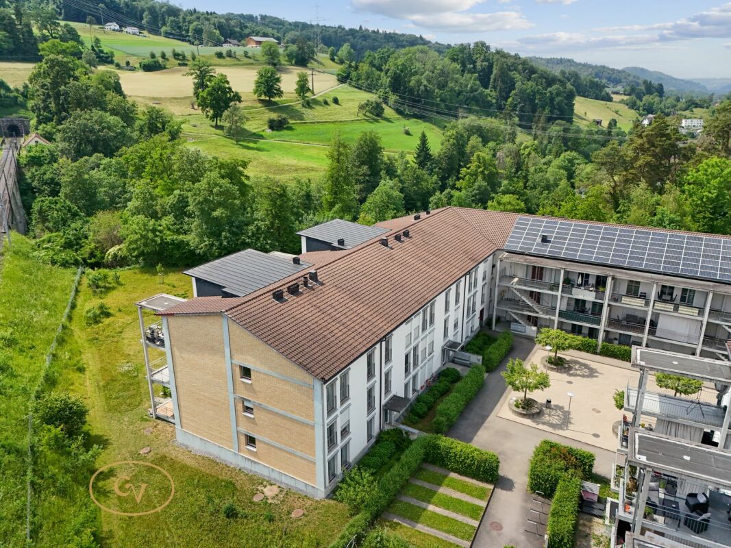 Luftaufnahme eines Wohngebäudes mit Innenhof und Photovoltaik