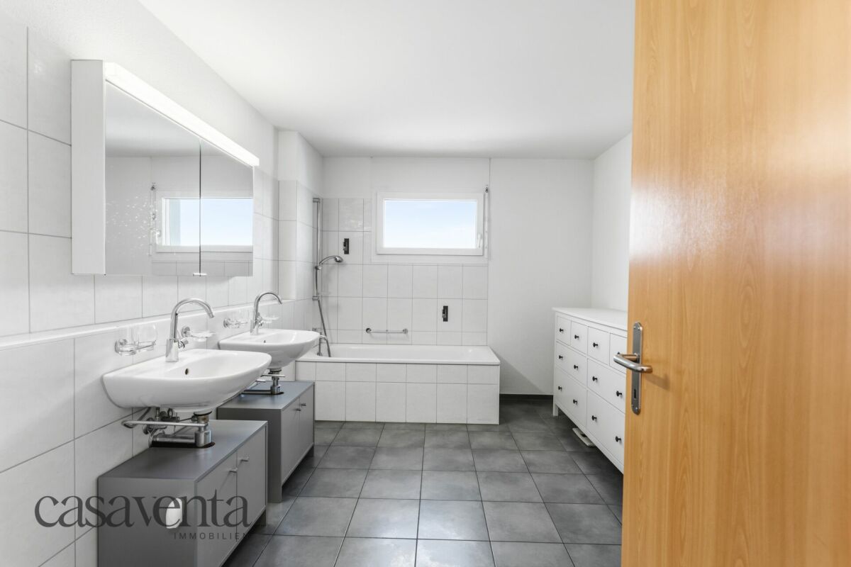 Helles Badezimmer mit Doppelwaschbecken und Badewanne