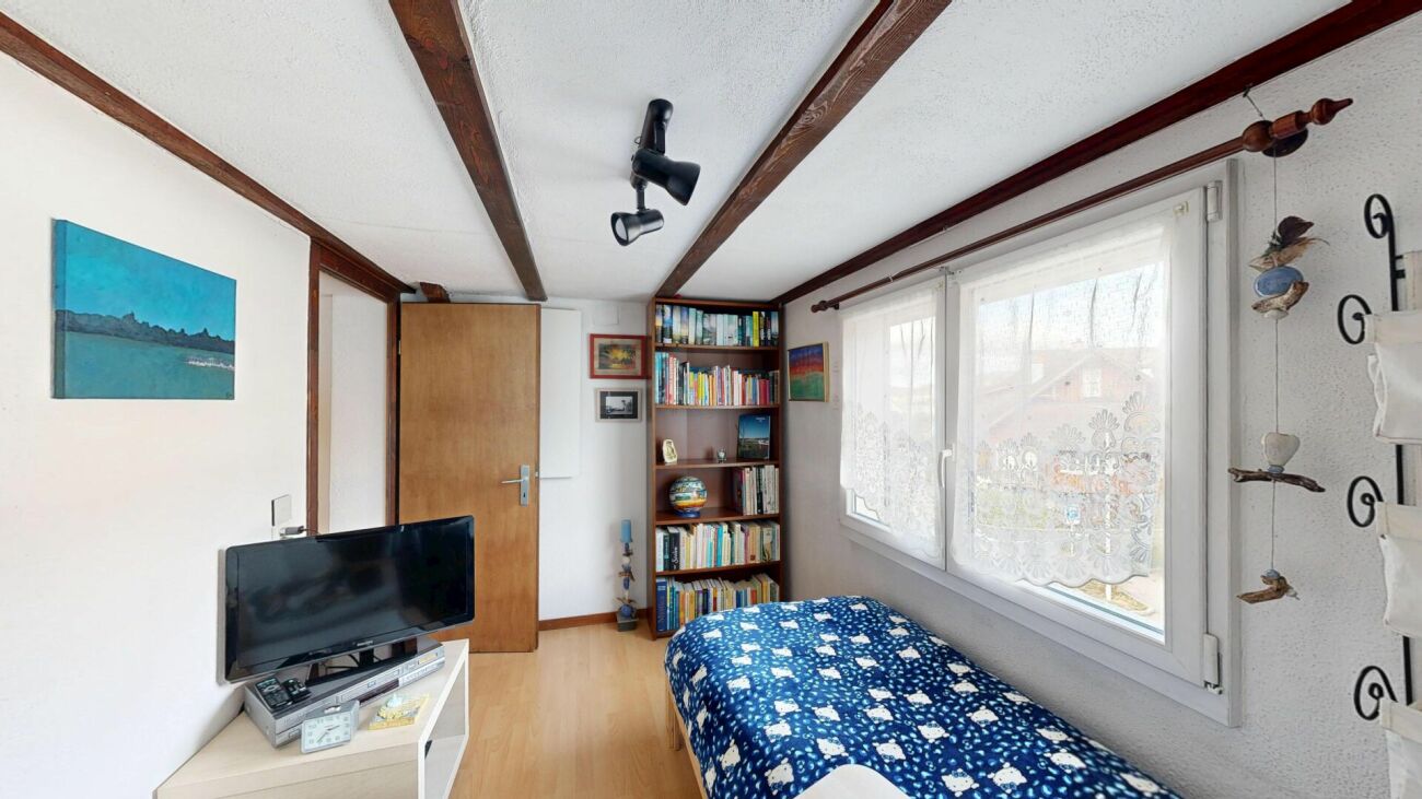 Helles kleines Schlafzimmer mit Holzdecke und Bücherregal