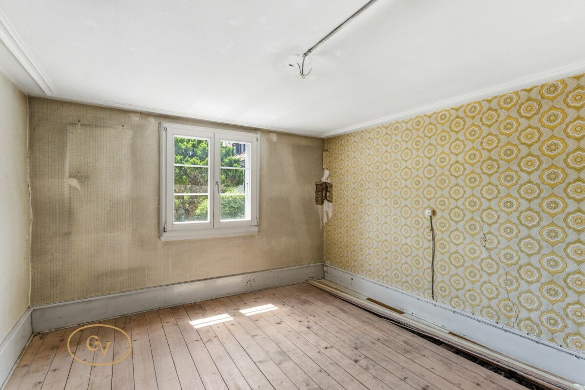 Renovierungsbedürftiges Zimmer mit Fenster und Tapeten