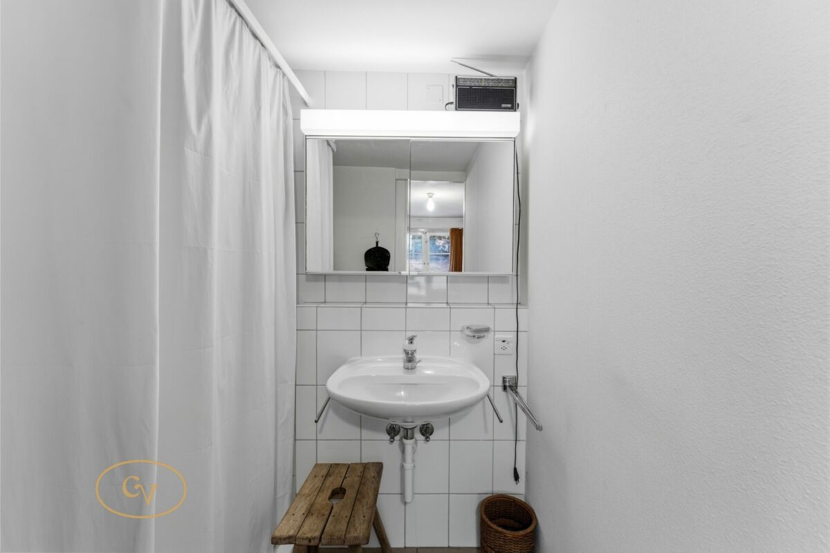 Kleines Badezimmer mit Waschbecken und Duschvorhang