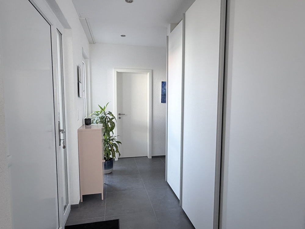 Heller Flur mit weißen Türen und grauem Boden