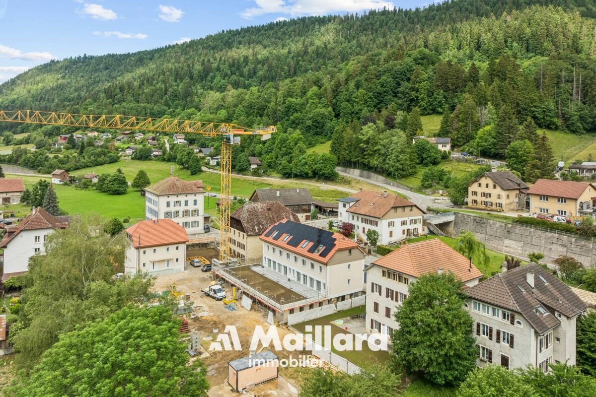 Luftaufnahme eines alpinen Ortes mit Wohngebäuden und Baustelle
