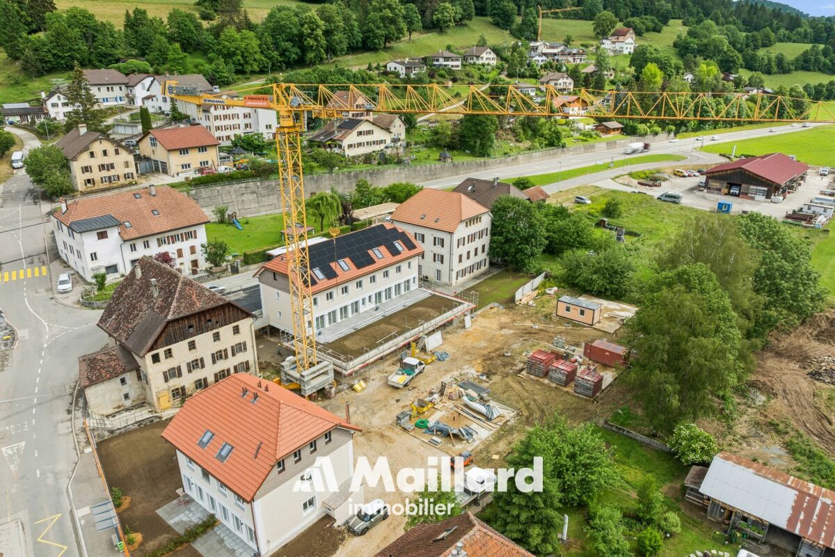 Luftaufnahme eines Dorfes mit Baustelle und Kran
