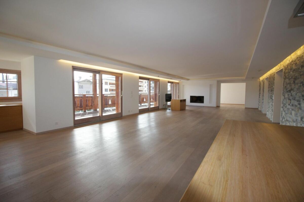 Großer leerer Wohnraum mit Balkon und Holzoptik