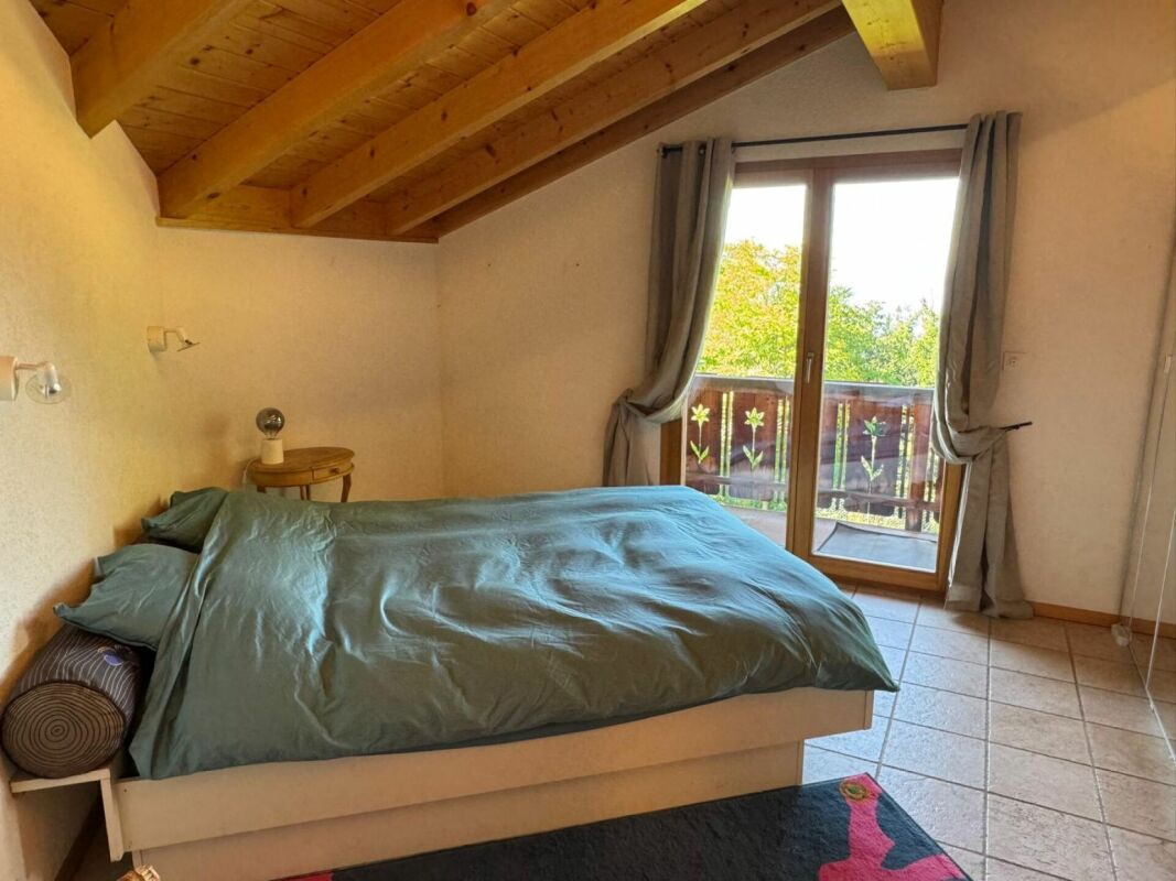 Schlafzimmer mit Holzbalkendecke und Balkon