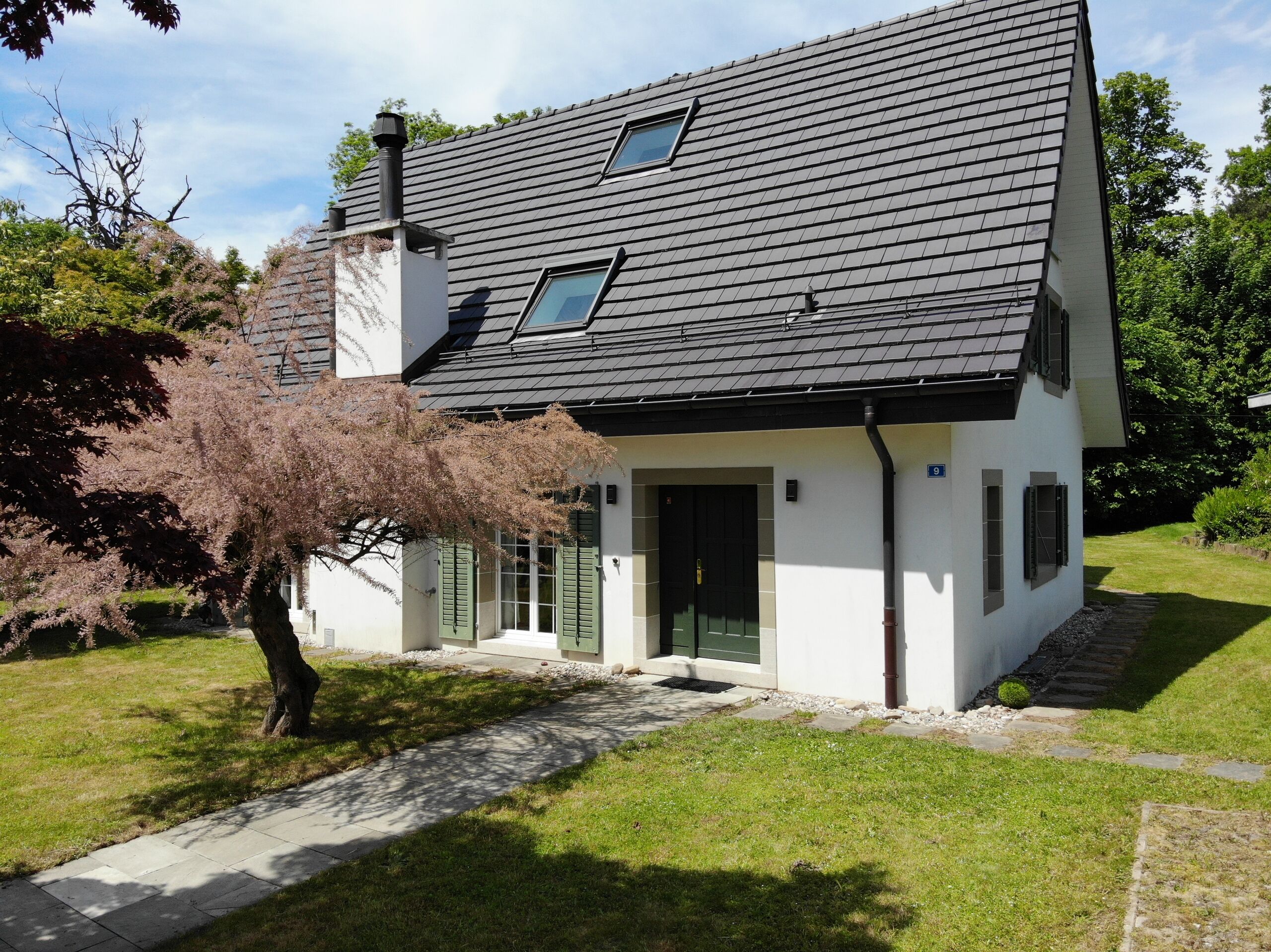 Einfamilienhaus mit steilem Schieferdach und Garten