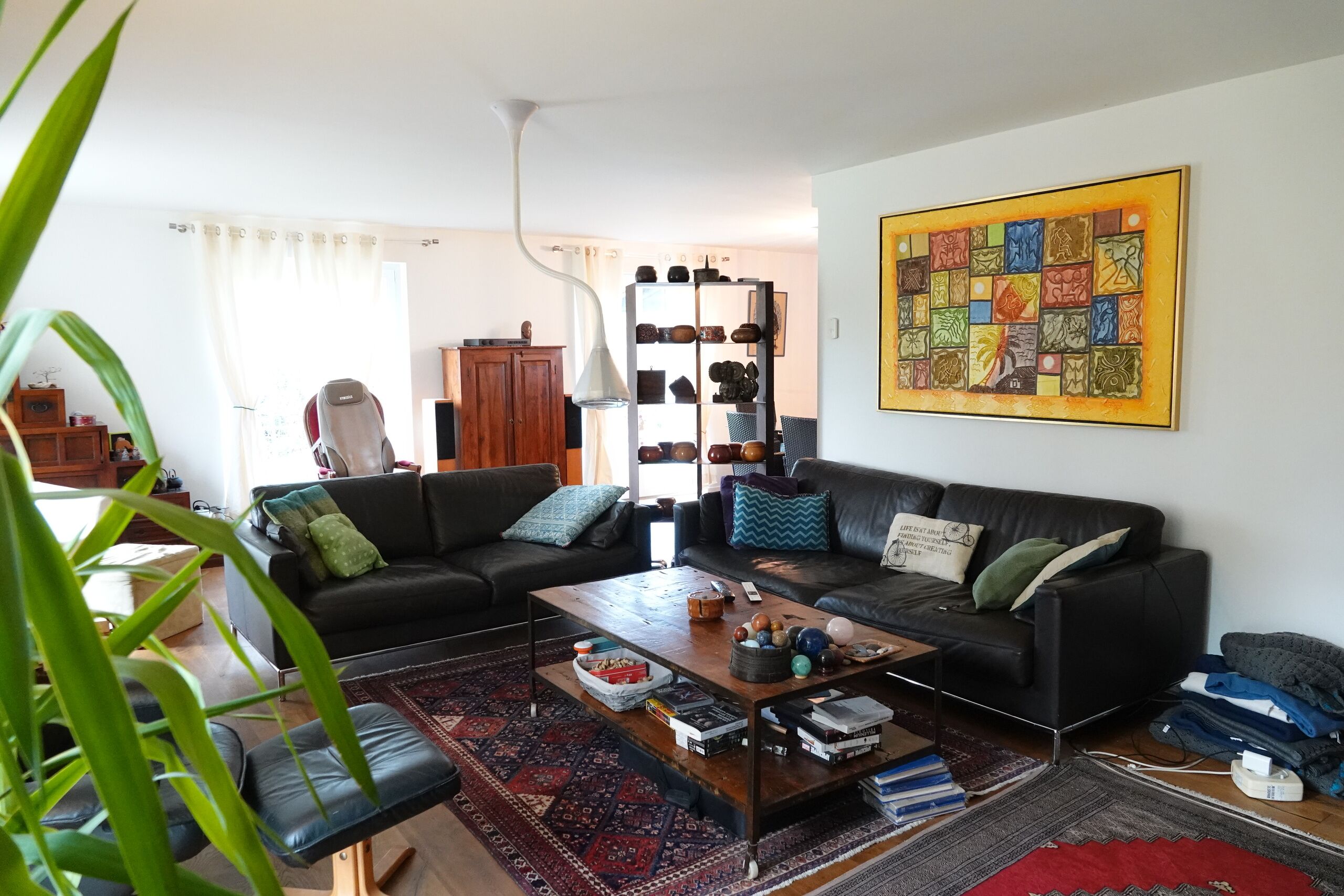 Helles Wohnzimmer mit schwarzer Ledergarnitur und Kunstwandbild