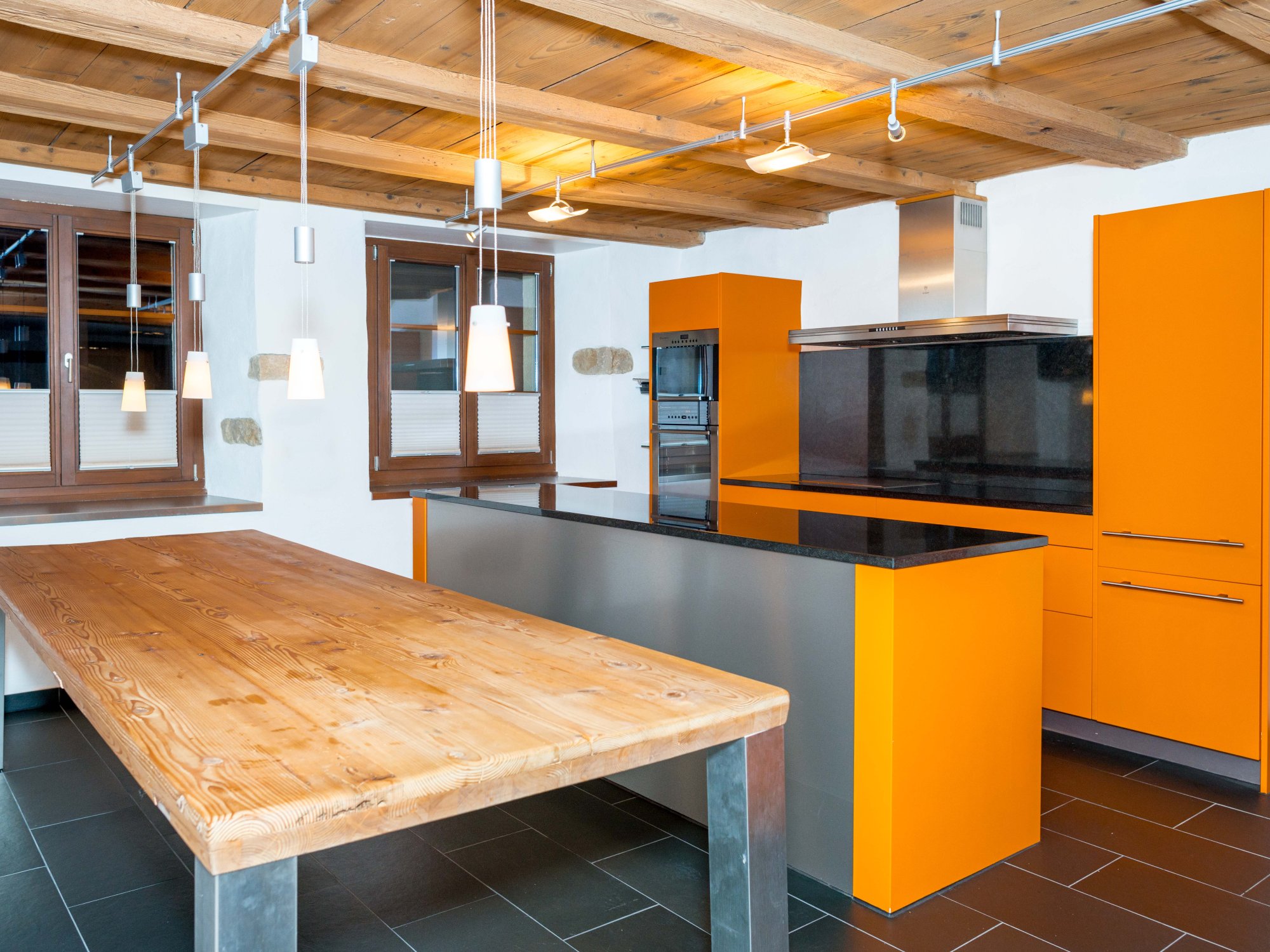 Moderne Küche mit Holzdecke und orangefarbenen Fronten