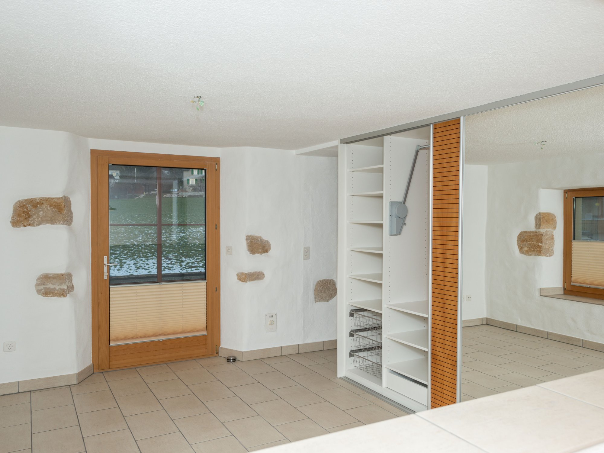 Heller Innenraum mit Fliesenboden und Einbauschrank