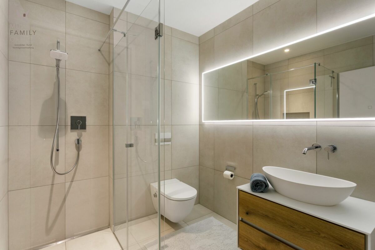 Modernes Badezimmer mit Walk-in-Dusche und beleuchtetem Spiegel