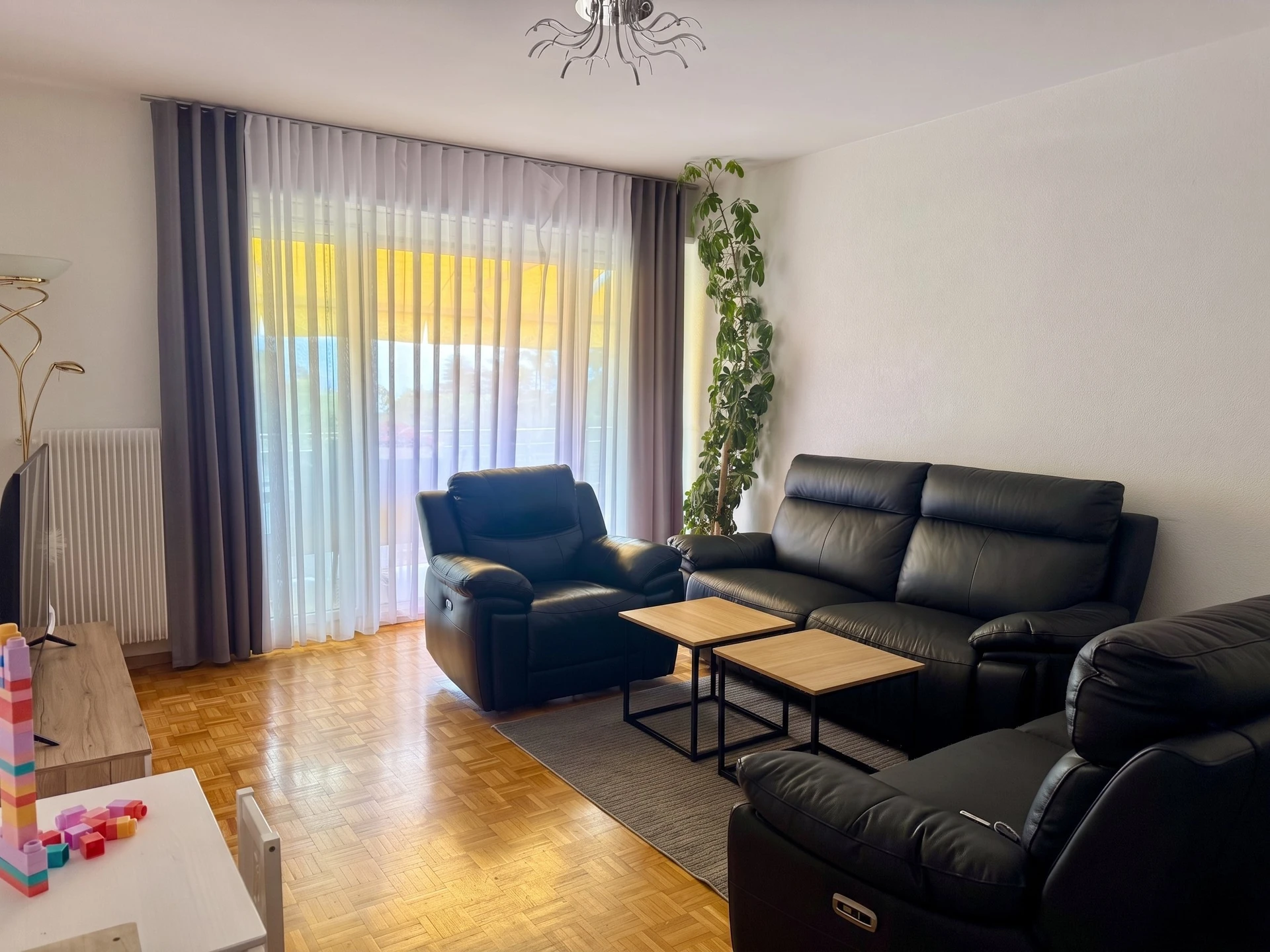 Helles Wohnzimmer mit schwarzer Ledersitzgruppe