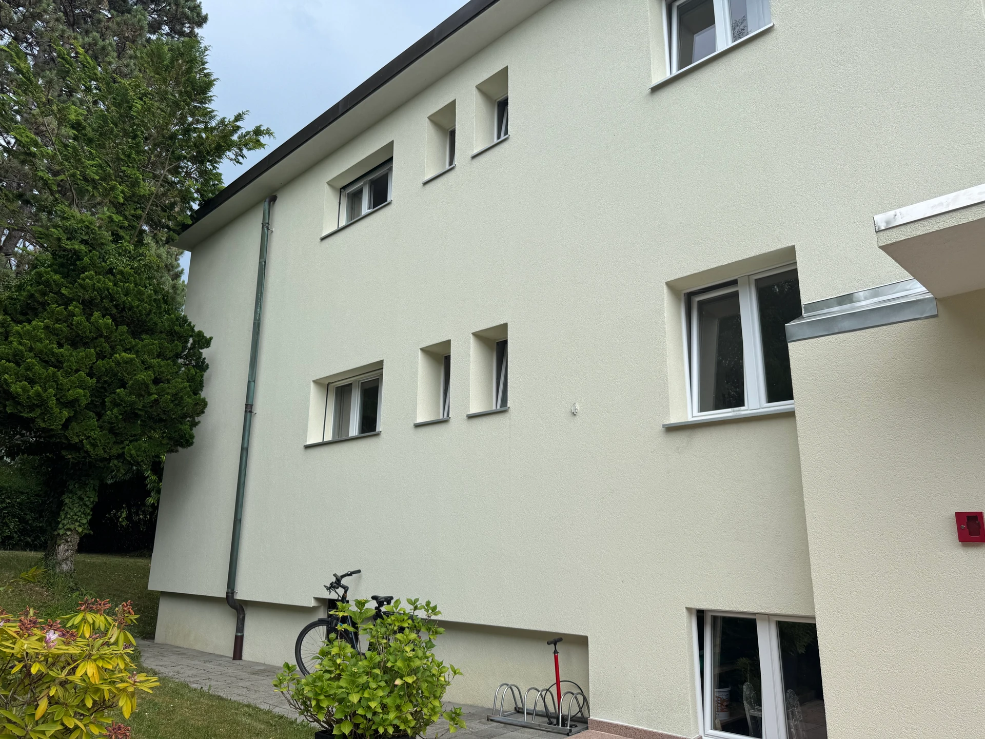 Außenansicht eines schlichten Mehrfamilienhauses mit Garten