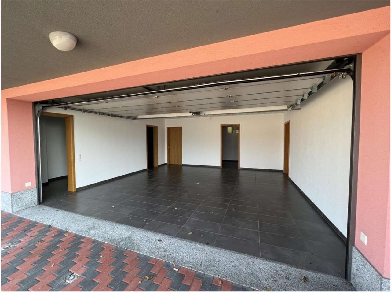 Offene Garage mit großen Fliesen und mehreren Türen