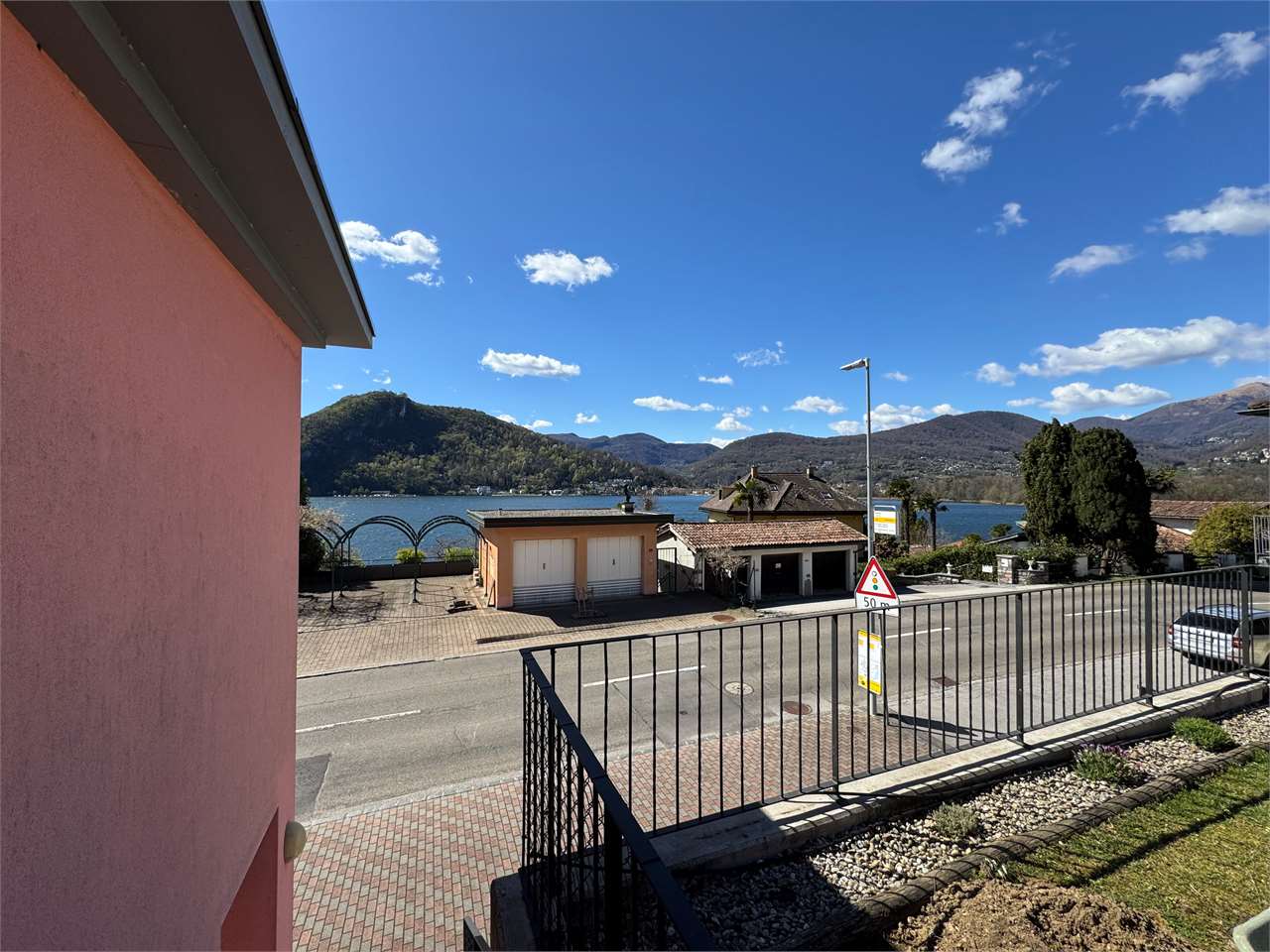 Seeblick von einem Balkon mit Straßen- und Bergpanorama