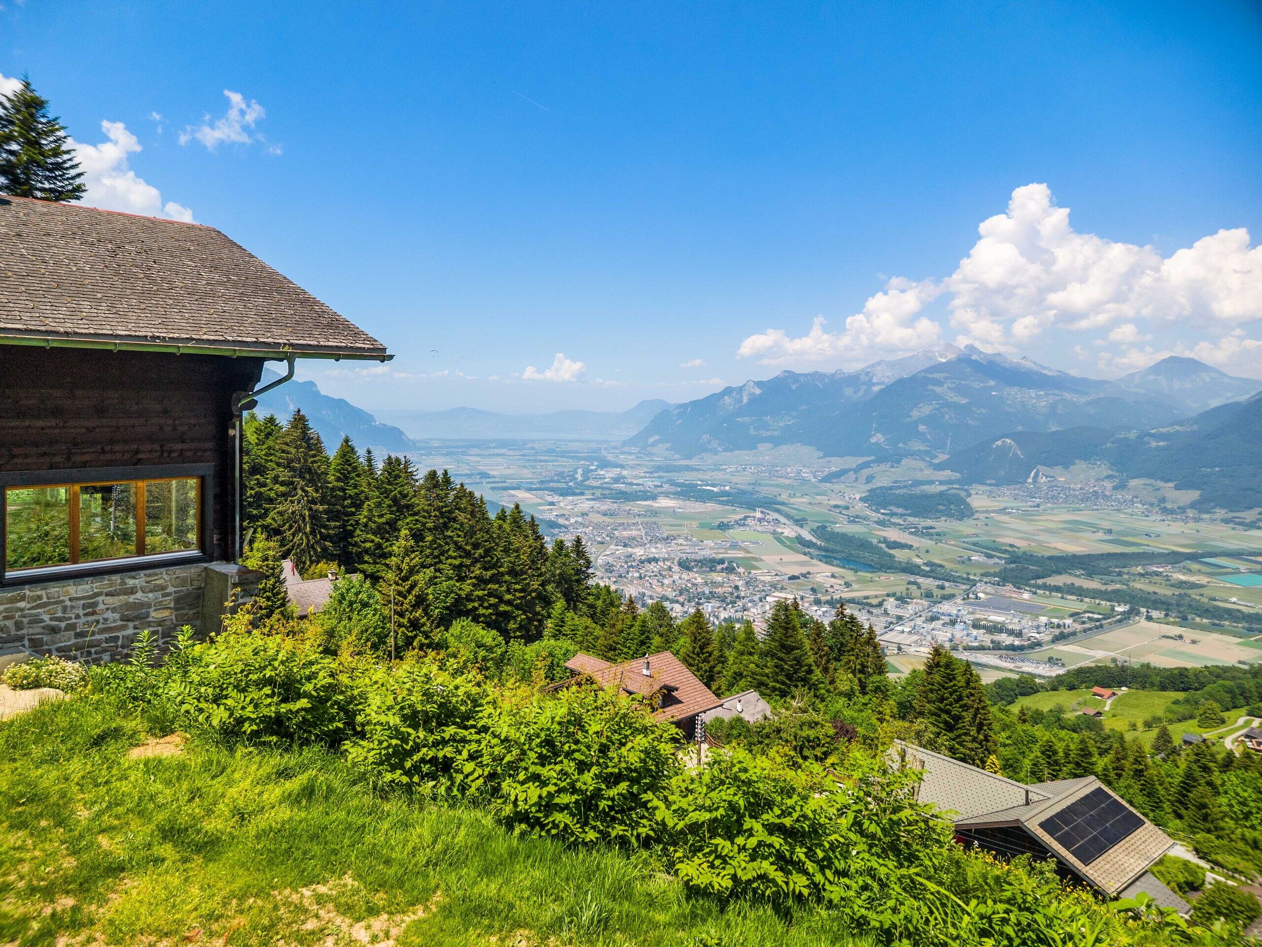 Alpenpanorama mit Berghang und Hausdach