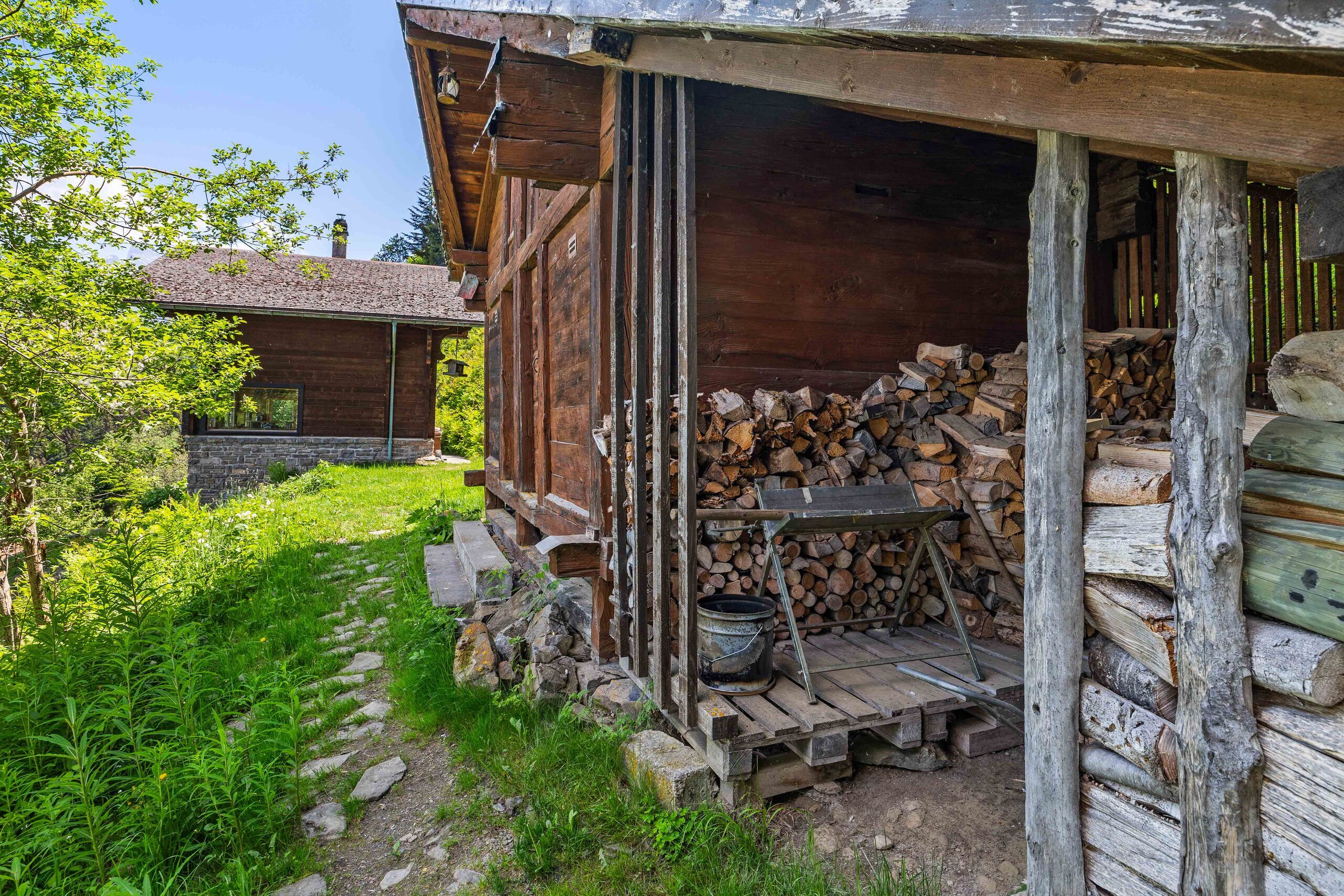 Rustikale Holzhütte mit Feuerholzlager im Grünen