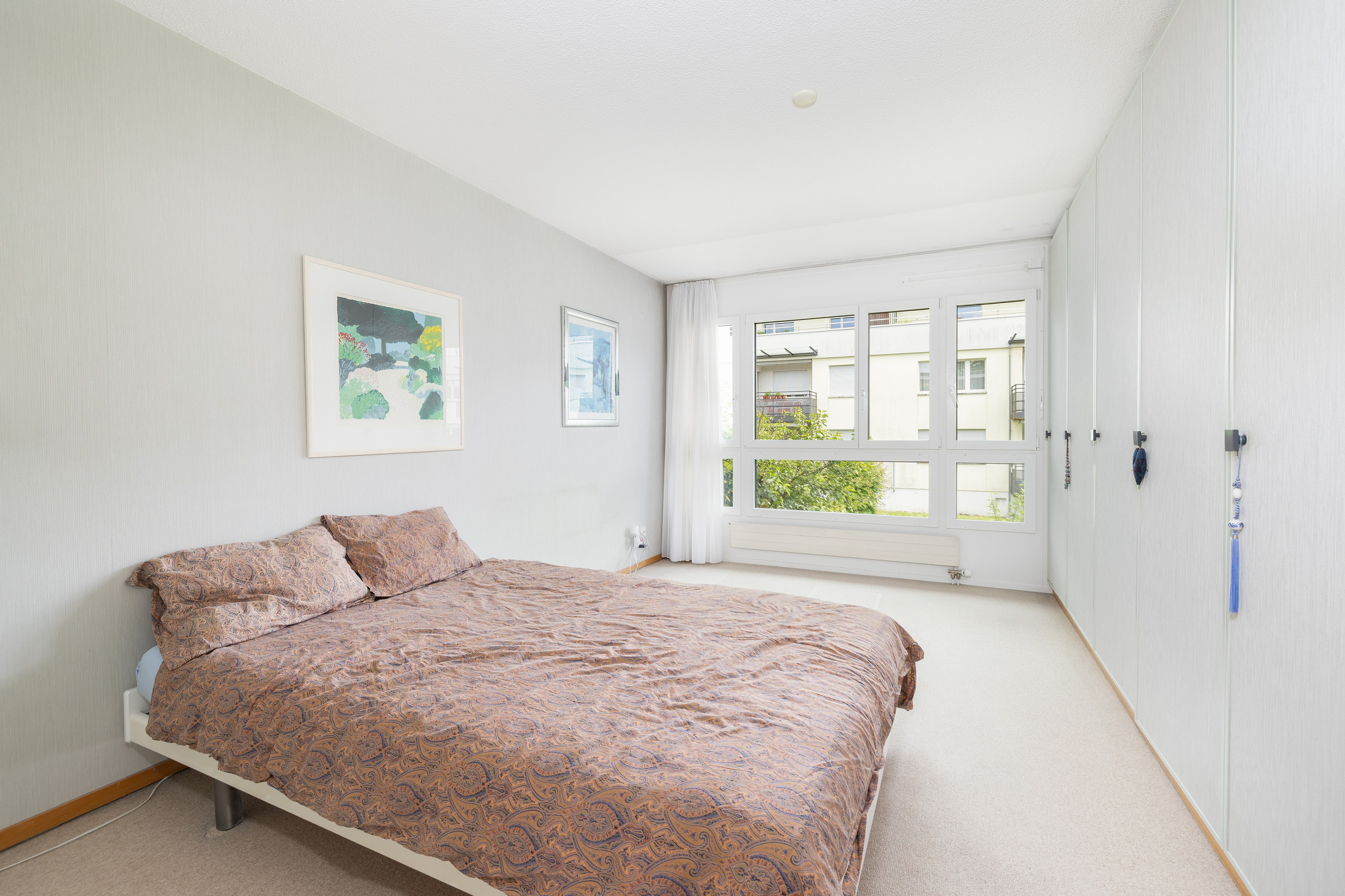 Helles Schlafzimmer mit großem Fenster und Bett