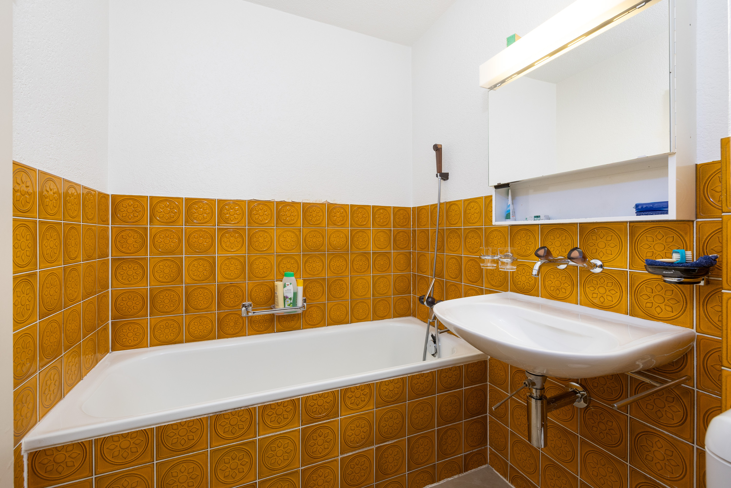 Bad mit gelben Wandfliesen und Wanne